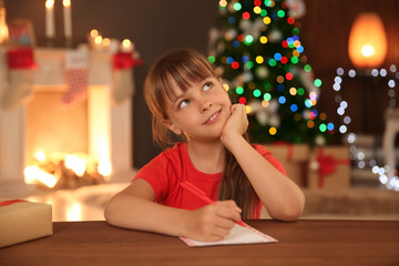 Little child writing letter to Santa at home. Christmas celebration