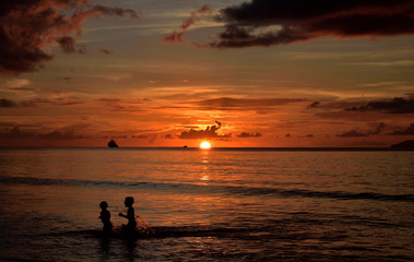 Spielende Kinder am Strand bei Sonnenuntergang