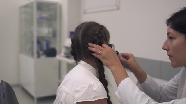 Nurse examines the ear of a girl