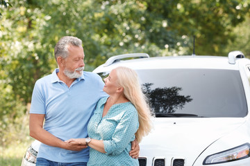 Happy senior couple posing near car outdoors