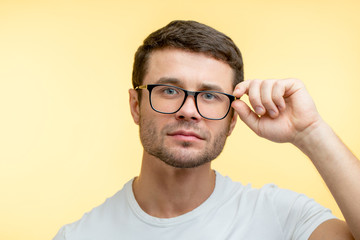 pleasant cute young man with beard holding his glasses