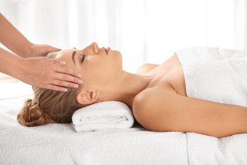 Relaxed woman receiving head massage in wellness center