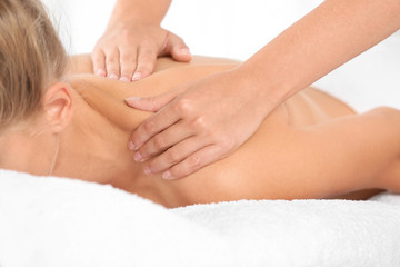 Relaxed woman receiving shoulders massage in wellness center