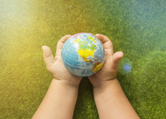 a mock globe in the hands of a man against the background of artificial grass. ecology, peace.