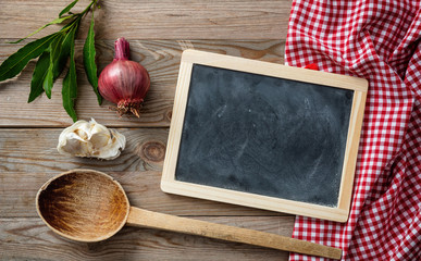 Blackboard and herbs on red tablecloth and wooden table, top view, copy space