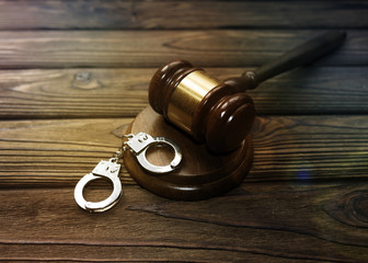 handcuffs for detaining criminals, a judge's hammer against the background of a wooden table....