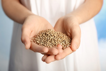 Woman holding heap of hemp seeds, closeup