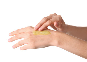 Woman applying hemp lotion on hand against white background, closeup