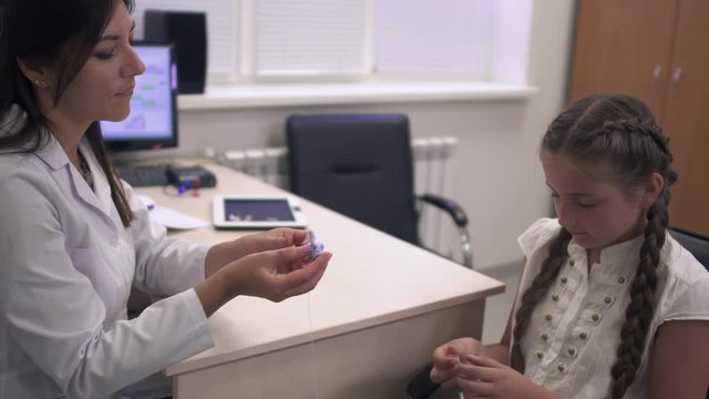 Doctor shows the girl hearing aids.