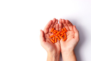 Orange pills in a female hands with a place for the text on a white background. Medecin, health.