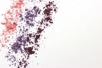 Multi-colored eye shadow scattered on a white background with space for text.