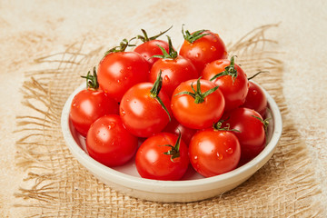 Fresh Red Cherry tomatoes in bowl on wooden background with textile napkin. Ingredients for cooking. 