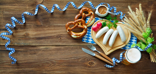Bavarian sausages with pretzels, sweet mustard and beer on rustic wooden table