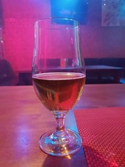 A glass of beer in the restaurant with different disco lights from dancing floor during party in the bar, restaurant, night club.