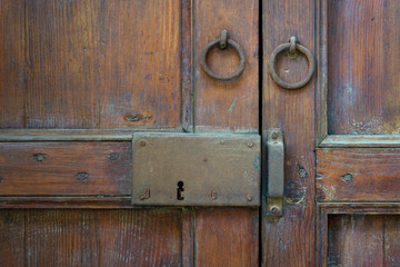 Fototapeta na wymiar Closeup of a wooden aged latch and two rusted ring door knockers over an ornate wooden door, Cairo, Egypt