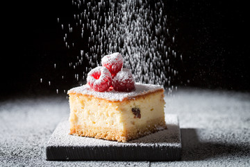 Falling powdered sugar on cheesecake with raspberries - obrazy, fototapety, plakaty