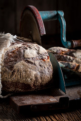 Closeup of tasty bread on slicer on dark table