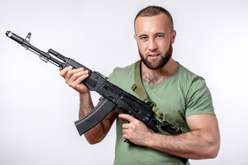 Bearded manful guy of european appearance in casual clothing looking at camera, holding sniper...