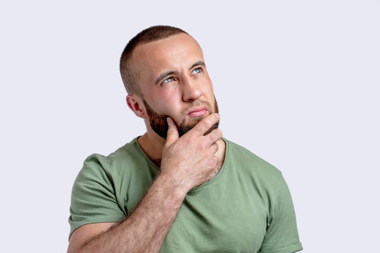 Caucasian Adult Pencive Man With Beard Thinking Doubting And Pondering, Working Out Decision, Keeping Hand Near His Chin And Looking Aside, Isolated On White Background.