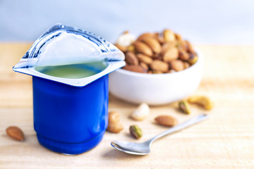 A breakfast of yogurt and a spoon placed on a wood table.