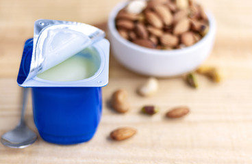 A breakfast of yogurt and a spoon placed on a wood table.