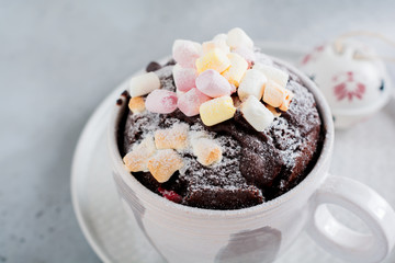 New Year's chocolate cake cooked in microwave oven in mug on vintage gray background texture. Top view.New Year card