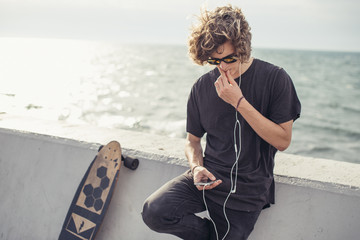 Serious looking surfer standing next to his longboard looking side near concrete wall © alfa27