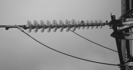 Obraz premium Fragment of high-voltage tower. Power line. Metalware. Black and white photo. BNW. Urban. Fragment