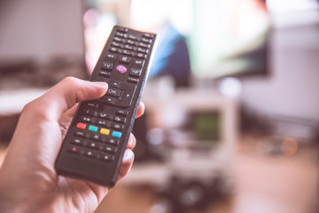 Fernbedienung vor Fernseher in Männerhand 