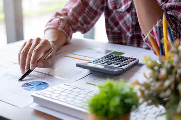 Closeup of a businessman financial specialist is working with calculator and computer to analyze a lot of data on financial report