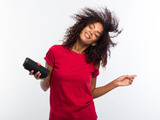Beautiful african american woman in red t-shirt enjoying and dancing at white background. Modern...