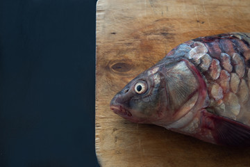 Delicious fresh fish (carp) on dark background for healthy food, diet or cooking concept