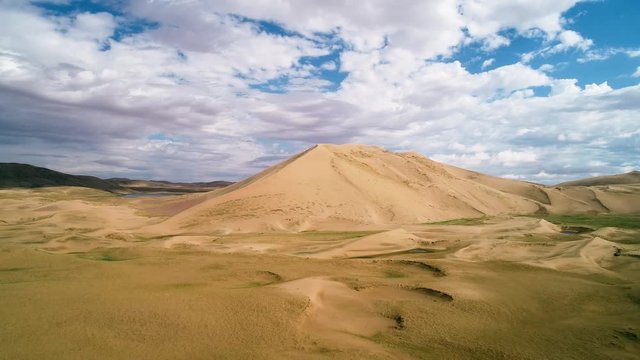 Panoramic view from above on a sandy desert with lakes. Flight over the barkhans in the desert.