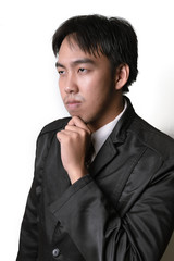 Handsome young man in full suit adjusting his necktie and looking at camera while standing against white background.