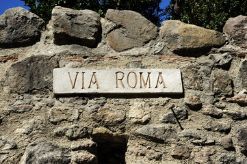 Marble street sign VIA ROMA in an ancient village in Italy. On the background a stone wall.