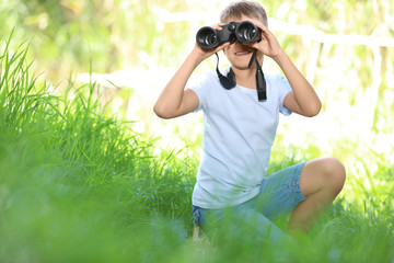 Little boy with binoculars outdoors. Summer camp