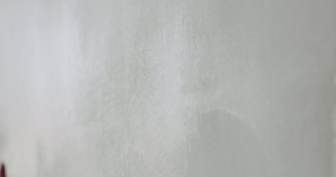 Slow motion handheld shot of worker applying putty on the wall