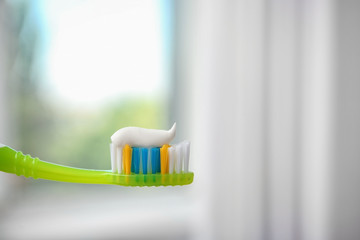 Toothbrush with paste on blurred background, closeup