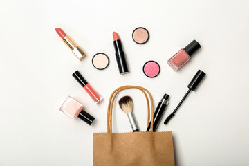 Flat lay composition with shopping bag and cosmetics on white background