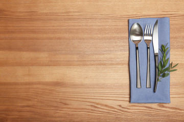 Cutlery and napkin on wooden background, top view. Table setting