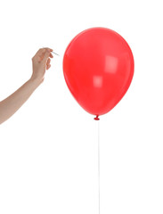 Woman piercing red balloon on white background © New Africa
