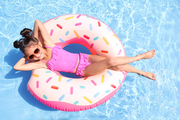 Little girl with inflatable ring in swimming pool