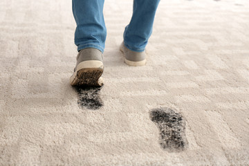 Person in dirty shoes leaving muddy footprints on carpet