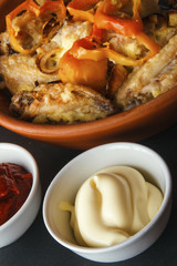Home-made mayonnaise for cooking lunch or dinner. Baked chicken wings on black background. Vertical view