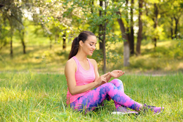 Young woman checking pulse outdoors on sunny day