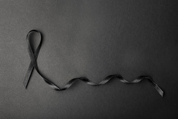 Black ribbon and space for text on dark background, top view. Funeral accessory