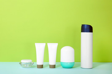 Different cosmetic products on table against color background