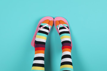 Woman wearing bright socks with flip-flops on color background