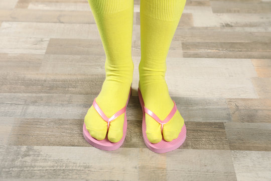 Woman wearing bright socks with flip-flops standing on floor