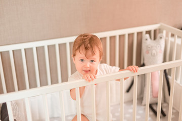 Cute little baby boy looking out of his bed